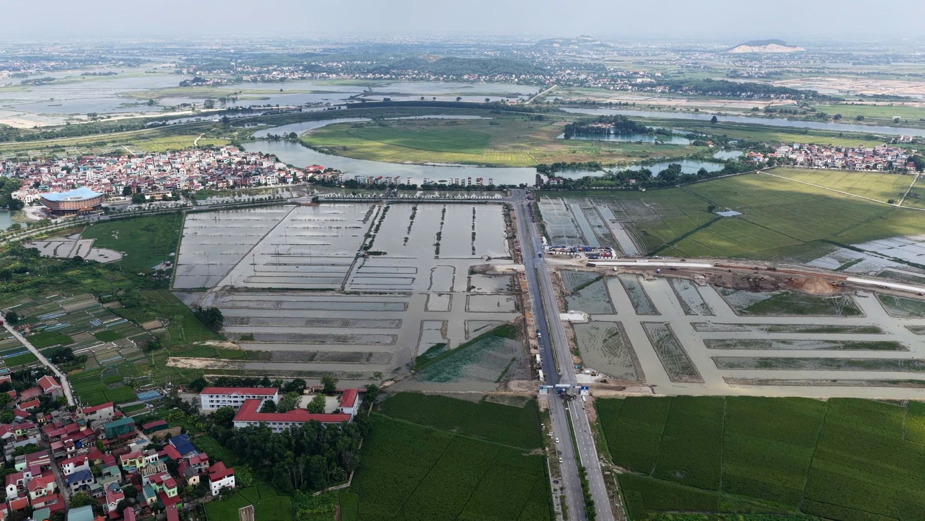 Vinhomes King Park Bắc Ninh - Toàn cảnh khu dự án: trục đường chính đã trải nhựa, các ô đất đã được phân lô; phía xa là khúc sông Cầu bao quanh khu bán đảo.